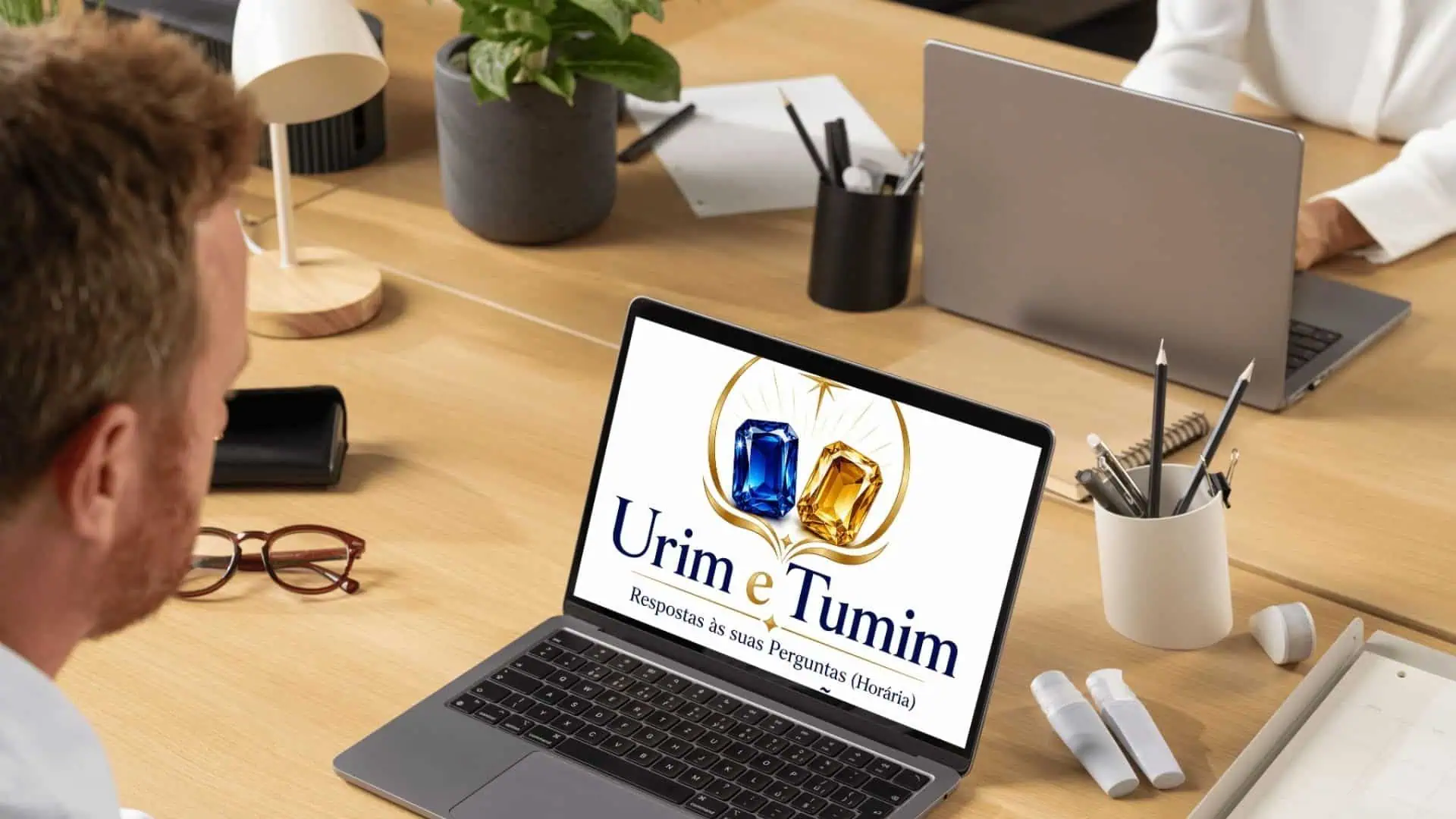 Pessoa utilizando notebook com o logotipo Urim e Tumim em ambiente de escritório moderno para consultas espirituais online por e-mail.