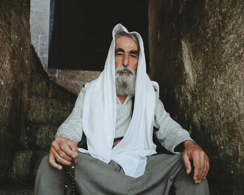 Kabbalista Avraham sentado em ambiente antigo, usando vestes tradicionais e manto branco, representante espiritual do mês hebraico de Cheshvan.