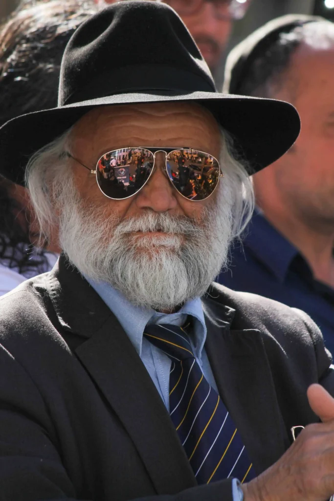 Kabbalista Shlomo com barba branca, chapéu preto e óculos escuros, representante espiritual do mês hebraico de Iyar.
