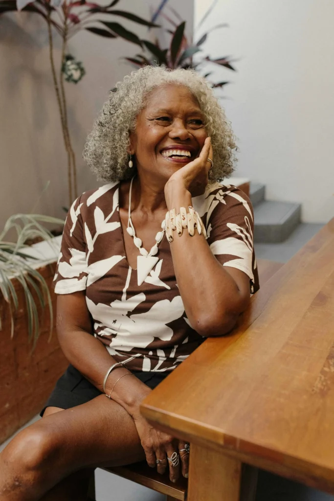 Kabbalista Tamar sorrindo sentada à mesa, representante espiritual do mês hebraico de Iyar.
