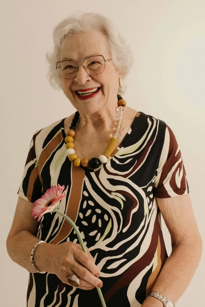 Kabbalista Yael sorrindo segurando uma flor rosa, representante espiritual do mês hebraico de Shevat.