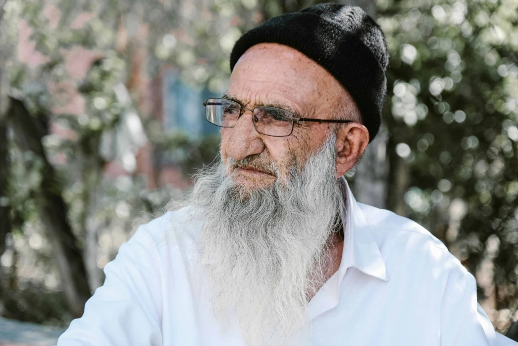 Kabbalista Yonatan com longa barba branca, óculos e vestes claras, representante espiritual do mês hebraico de Sivan.